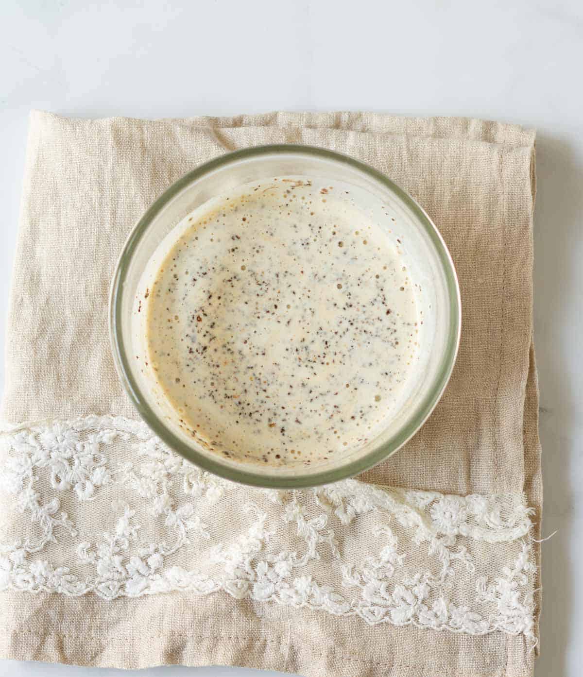 Cream mixed with tea leaves and spices in a small bowl.