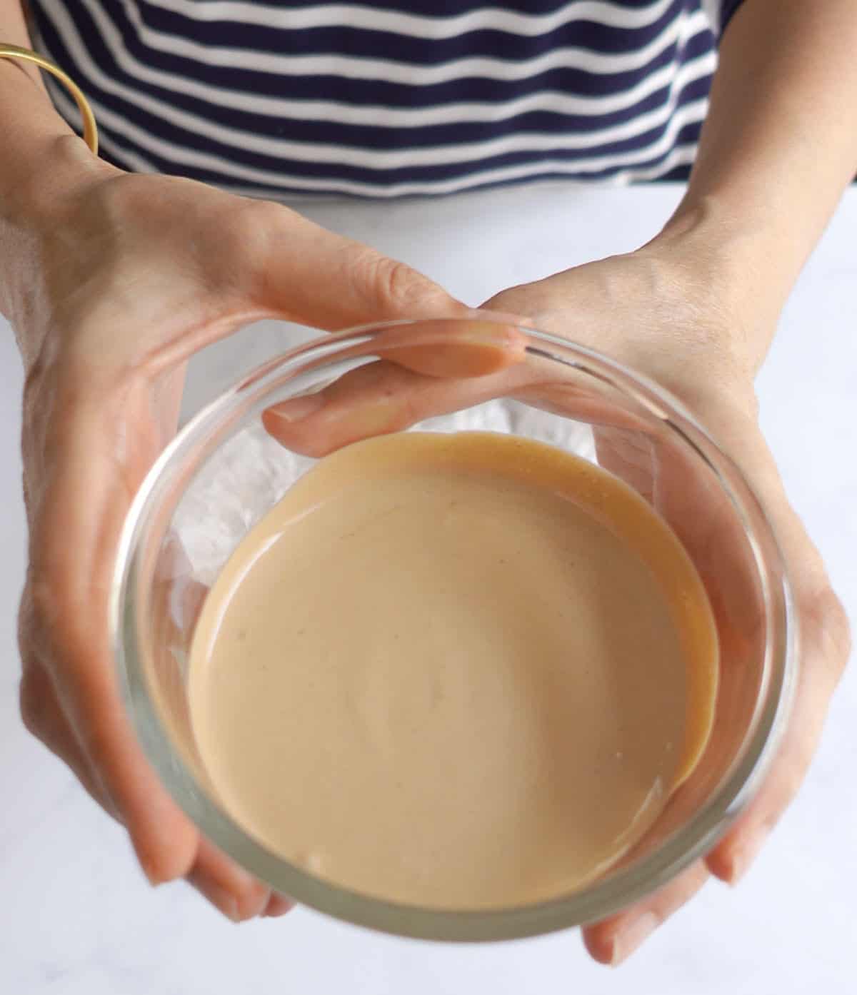 2 hands holding a small bowl of chai-infused cream.