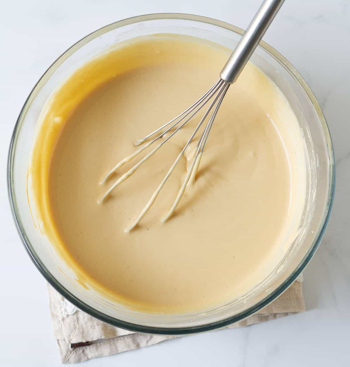 Chai-spiced cheesecake batter with a whisk in a mixing bowl.