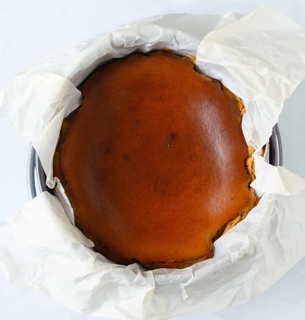 Baked masala chai Basque cheesecake in a parchment-lined cake pan.